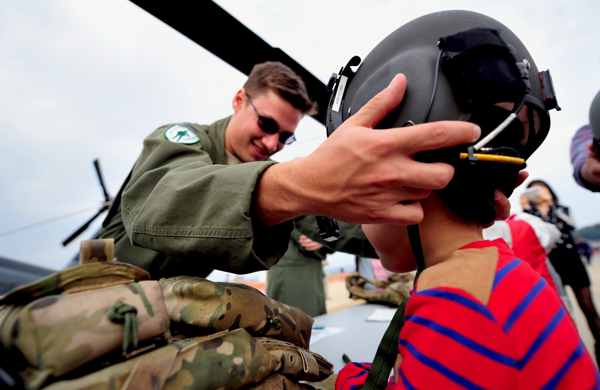 Capt. Elliott Milliken, an HH-60 Pave Hawk pilot with the 33rd Rescue Squadron, helps a child from the local community near Osan Air Base, Republic of Korea, put on a helmet during Osan's Air Power Day, Oct. 20, 2012. The Airmen participated in the air show to help highlight the relationship between them and the Koreans through public demonstrations of military equipment and personnel. (U.S. Air Force photo/Staff Sgt. Sara Csurilla)