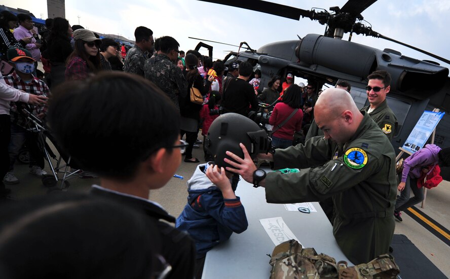 Capt. John Larson, an HH-60 Pave Hawk pilot with the 33rd Rescue Squadron, helps a child from the local community near Osan Air Base, Republic of Korea, put on a helmet during Osan's Air Power Day, Oct. 20, 2012. The Airmen participated in the air show to help highlight the relationship between them and the Koreans through public demonstrations of military equipment and personnel. (U.S. Air Force photo/Staff Sgt. Sara Csurilla)