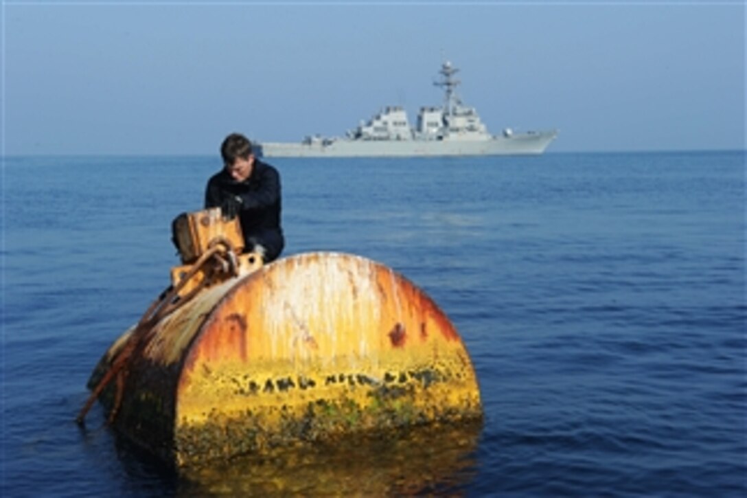 U.S. Navy Petty Officer 3rd Class Anthony Scott looks for identification information during a salvage survey of a drifting buoy in the Arabian Sea on Oct. 9, 2012.  Scott is a Navy diver assigned to Mobile Diving and Salvage Unit 1.  The guided-missile destroyer USS Benfold (DDG 65) waits nearby for Scott to complete his survey.   