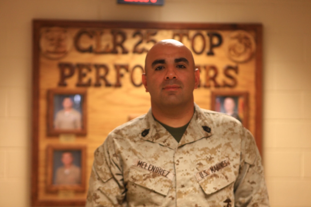Gunnery Sgt. Jesus M. Melendrez, the operations chief for Combat Logistics Regiment 25, 2nd Marine Logistics Group, poses in front of the CLR-25 Top Performers panel aboard Camp Lejeune, N.C., Oct. 18, 2012. Melendrez dedicates most of his evenings and weekends to coaching youth sports at the base, and he has earned a reputation as an outstanding youth mentor within his unit.