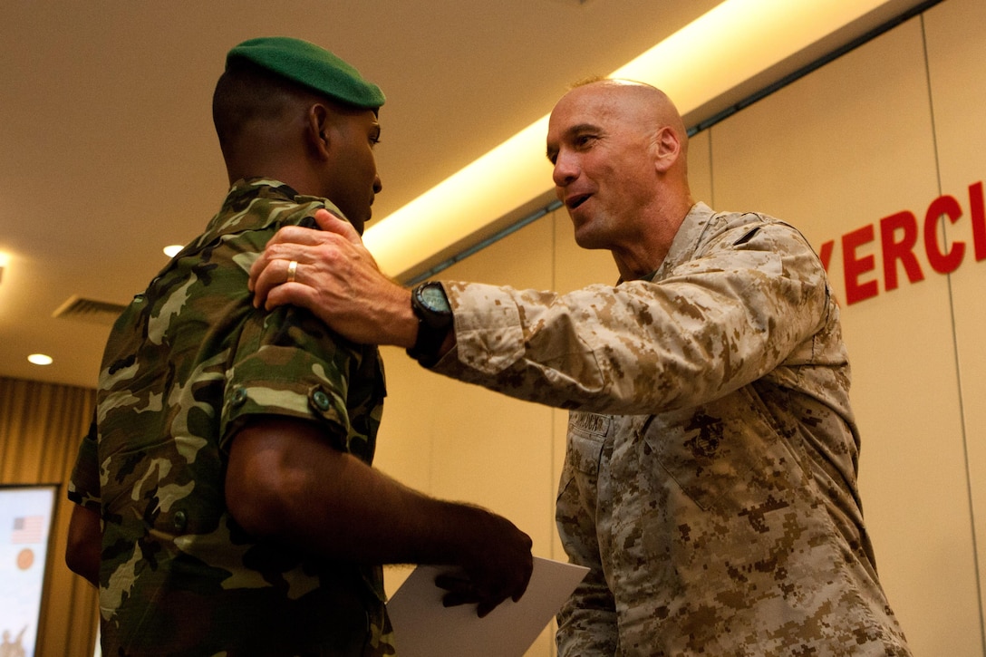 Brig. Gen. Richard L. Simcock, deputy commanding general of U.S. Marine Corps Forces, Pacific, congratulates a Maldivian Marine and hands him a certificate here Oct. 17, during the closing ceremony for Exercise Coconut Grove 2012. The exercise is a bilateral training event conducted bi-annually between the U.S. Marine Corps and the Maldivian National Defense Force, focusing on general military skills.