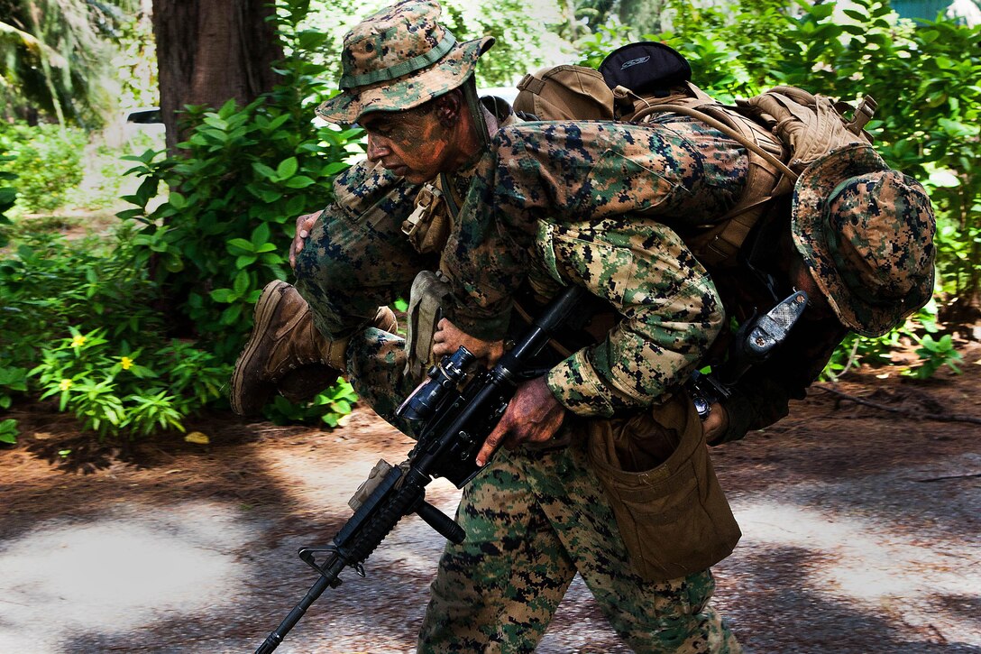 Sgt. Sergio Zacarias, a squad leader with Company A, 1st Battalion, 4th Marine Regiment, carries an "injured" Marine out of harm's way during a raid here Oct. 16 as part of Exercise Coconut Grove 2012. The exercise is a bilateral training event conducted bi-annually between the U.S. Marine Corps and the Maldivian National Defense Force.