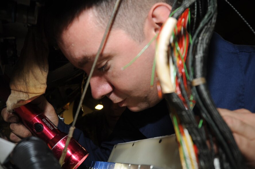 U.S. Air Force Staff Sgt. Kenneth Boswell, 14th Aircraft Maintenance Unit electrical and environmental craftsman, uses a flashlight to look for a fallen nut during a harness removal operation at Misawa Air Base, Japan, Oct. 11, 2012. Boswell was the primary maintainer on the harness removal operation, accompanied by four to six others. (U.S. Air Force photo/Airman 1st Class Kenna Jackson) 
