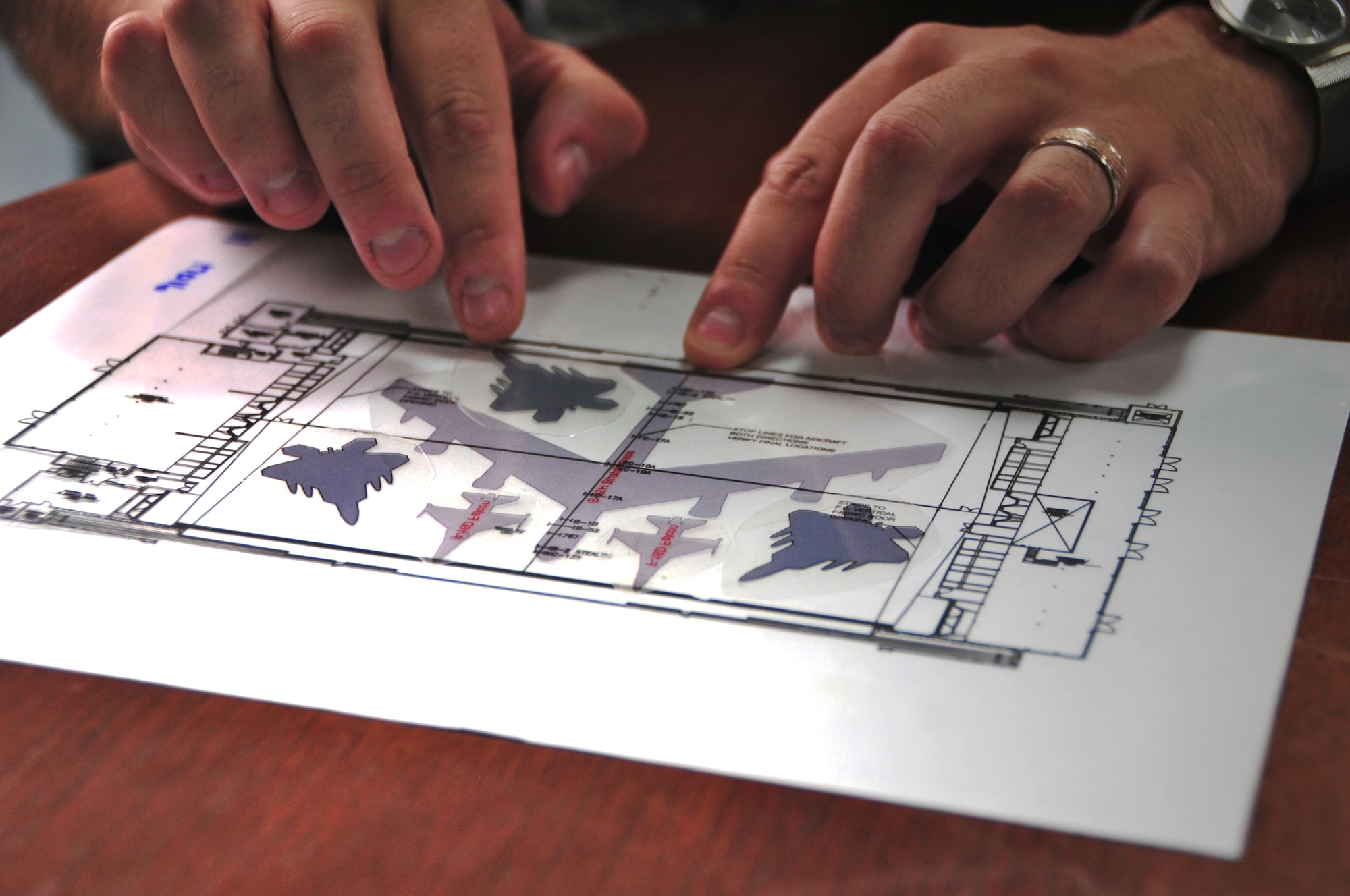 ANDERSEN AIR FORCE BASE, Guam -- Capt. Christopher Smith, 36th Maintenance Squadron operations officer, utilizes scaled transparencies of a hangar and aircraft models in order to demonstrate how the aircraft can be situated in hangars here, Oct. 9.  Whenever a decision is made that an evacuation is not necessary, but there are impending high winds, the units are required to place as many aircraft in the hangars as possible to protect them from strong winds and flying debris. (U.S. Air Force photo by Airman 1st Class Marianique Santos/Released)