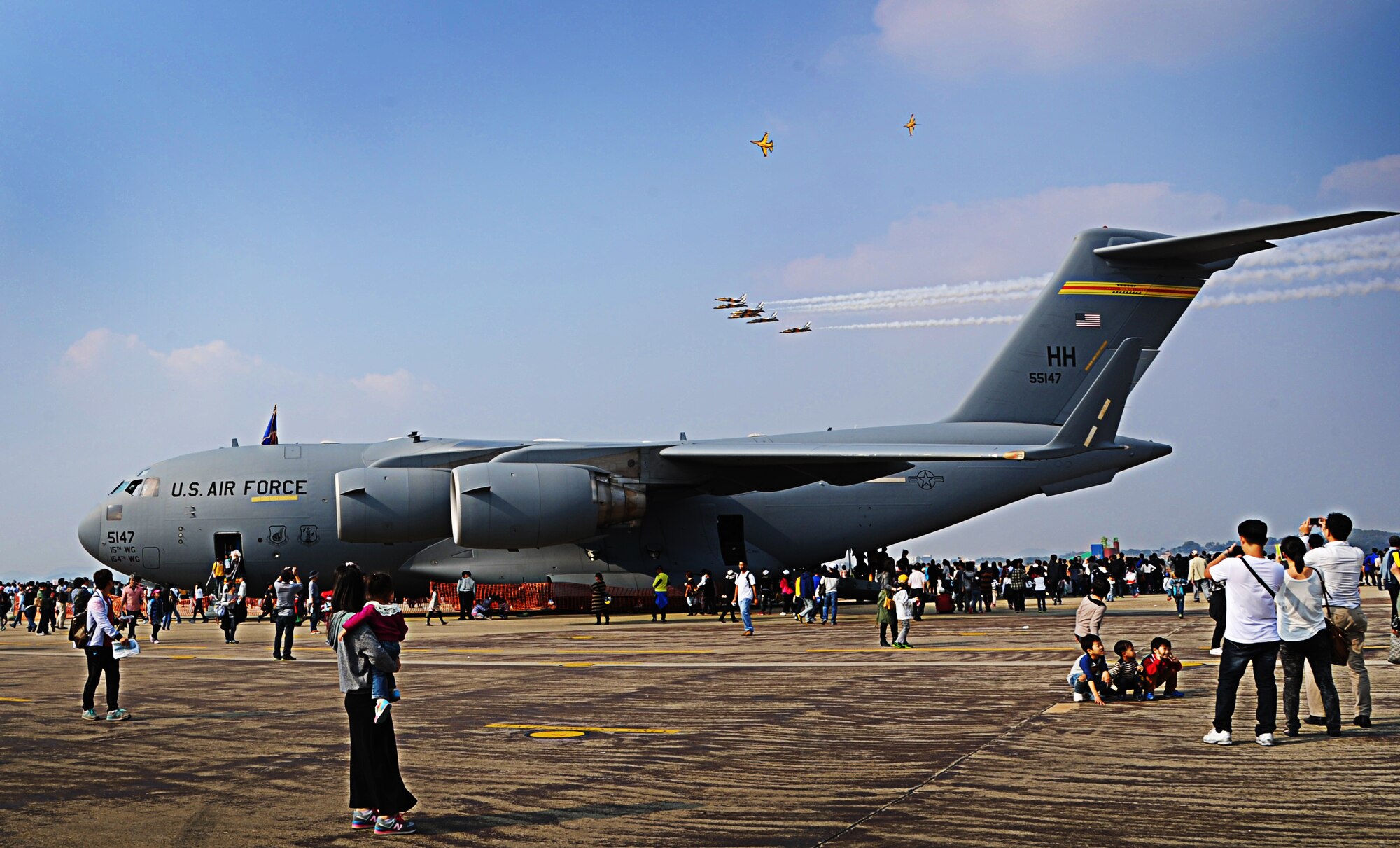 Spectators at the "Air Power Day" tour a C-17 Globemaster III from the 15th Wing at Joint Base Pearl Harbor-Hickam, Hawaii, while the Black Eagles, the Republic of Korea's premiere aerial demonstration team, fly overhead Oct. 20 at Osan Air Base, ROK. Consisting of aircrew members from the 535th Airlift Squadron at JBPHH, the demonstration team operating the C-17 fulfills a rare mission of showcasing C-17 capabilities at air shows in the Pacific theater and western United States. (U.S. Air Force photo by Senior Airman Lauren Main) 