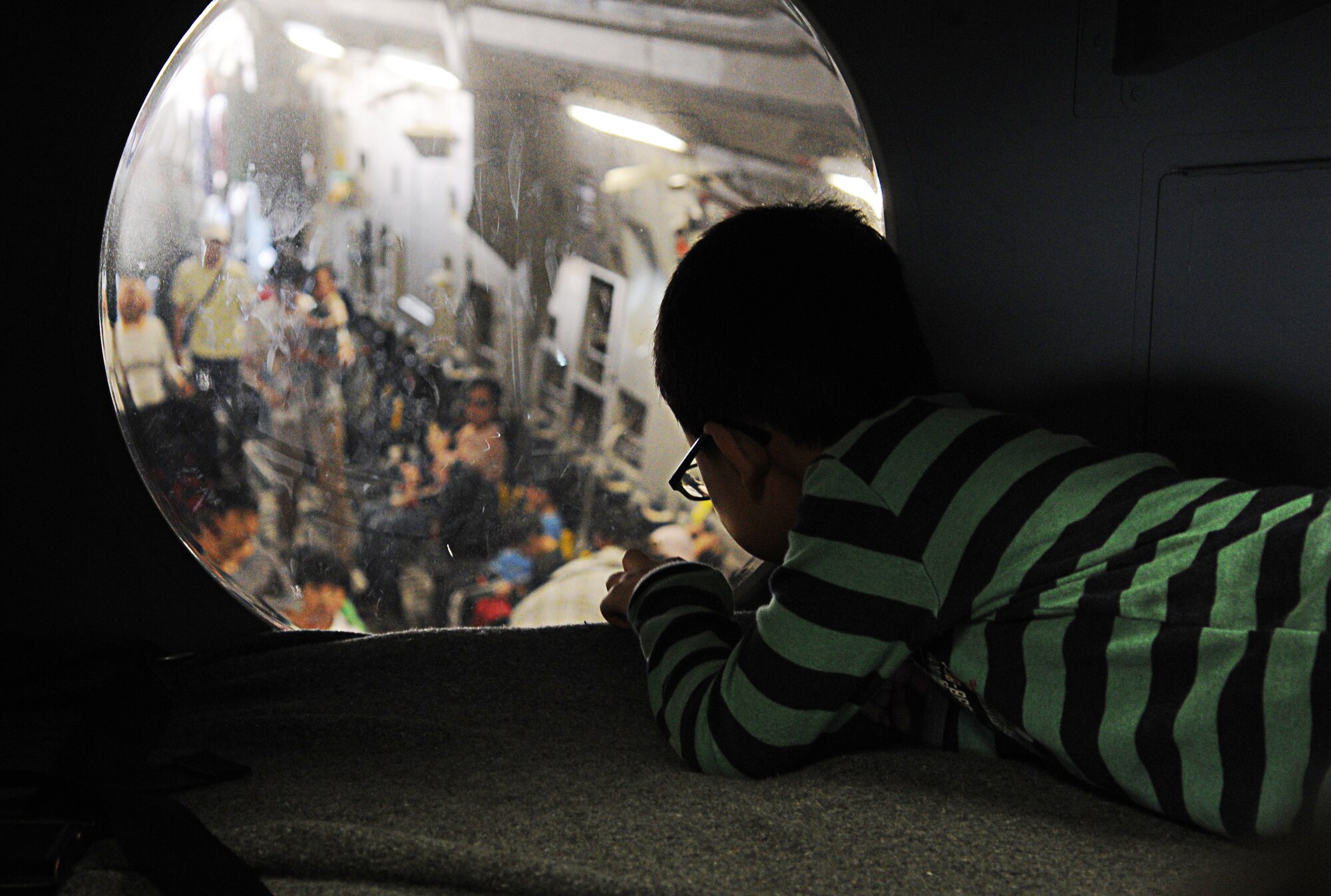 A Korean boy peers through a flight deck window into the cargo bay of a C-17 Globemaster III from the 15th Wing at Joint Base Pearl Harbor-Hickam, Hawaii, during the "Air Power Day" air show Oct. 20 at Osan Air Base, Republic of Korea. Consisting of aircrew members from the 535th Airlift Squadron at JBPHH, the demonstration team operating the C-17 fulfills a rare mission of showcasing C-17 capabilities at air shows in the Pacific theater and western United States. (U.S. Air Force photo by Senior Airman Lauren Main) 