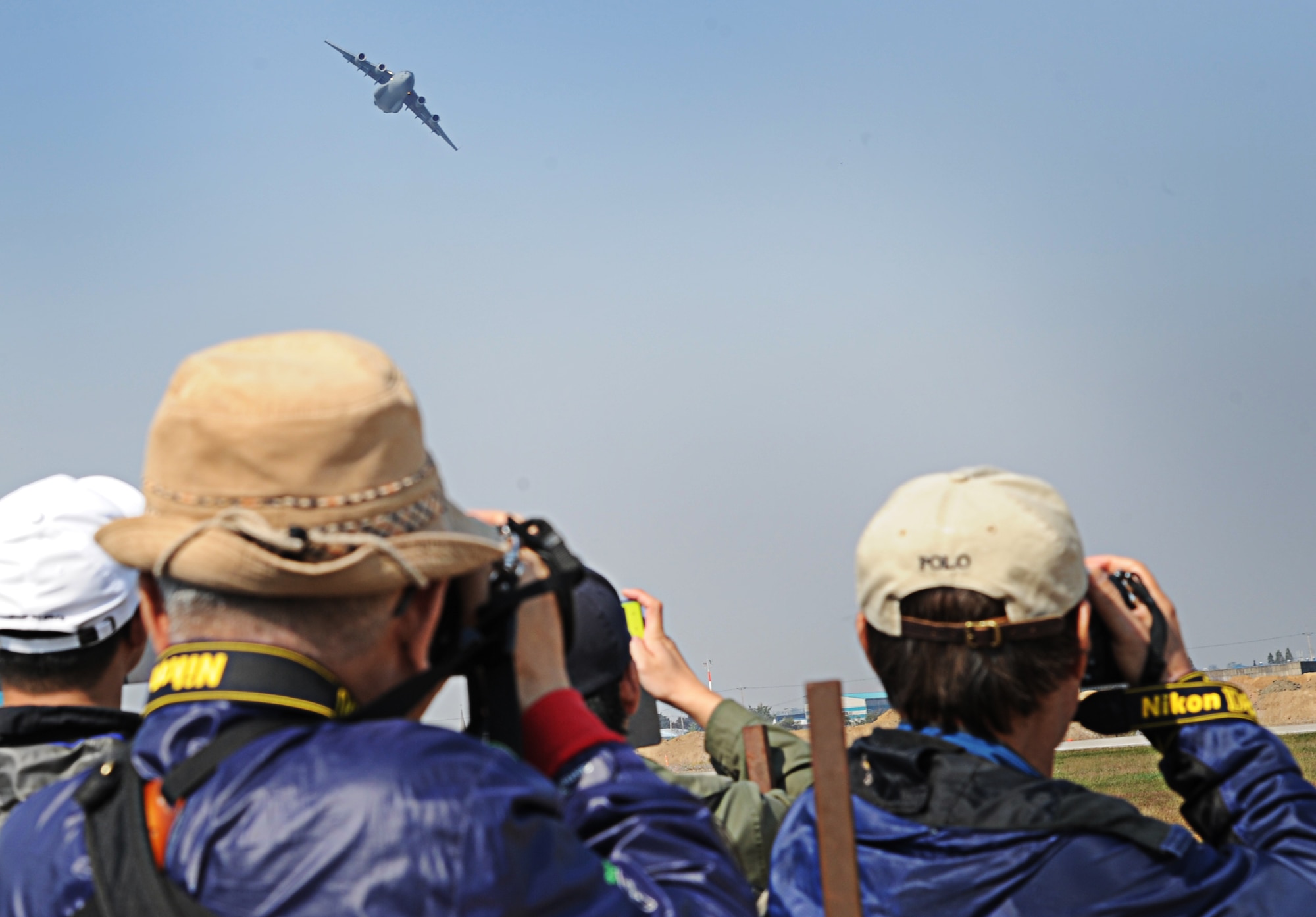 Spectators at the "Air Power Day" air show take photos of a C-17 Globemaster III from the 15th Wing in at Joint Base Pearl Harbor-Hickam, Hawaii, performing an aircraft demonstration Oct. 20 at Osan Air Base, Republic of Korea. Consisting of aircrew members from the 535th Airlift Squadron at JBPHH, the demonstration team operating the C-17 fulfills a rare mission of showcasing C-17 capabilities at air shows in the Pacific theater and western United States. (U.S. Air Force photo by Senior Airman Lauren Main)