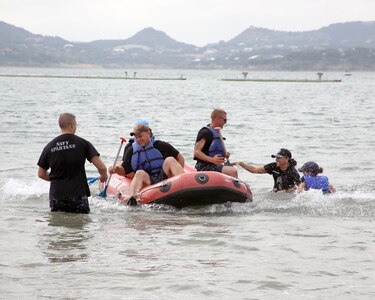 (From left to right)  Daniel Albright and Scott Lewis of the Navy Spartans team are pulled off their raft by fellow team members after completing the rafting portion of the Rambler 120 triathlon event held Oct. 20 at Joint Base San Antonio Recreation Park, Canyon Lake, Texas.  The seventh annual Rambler 120 includes a 22-mile bike course, a 6-mile run and a 2-mile rafting course. (U.S. Air Force photo by Dan J. Solis)

