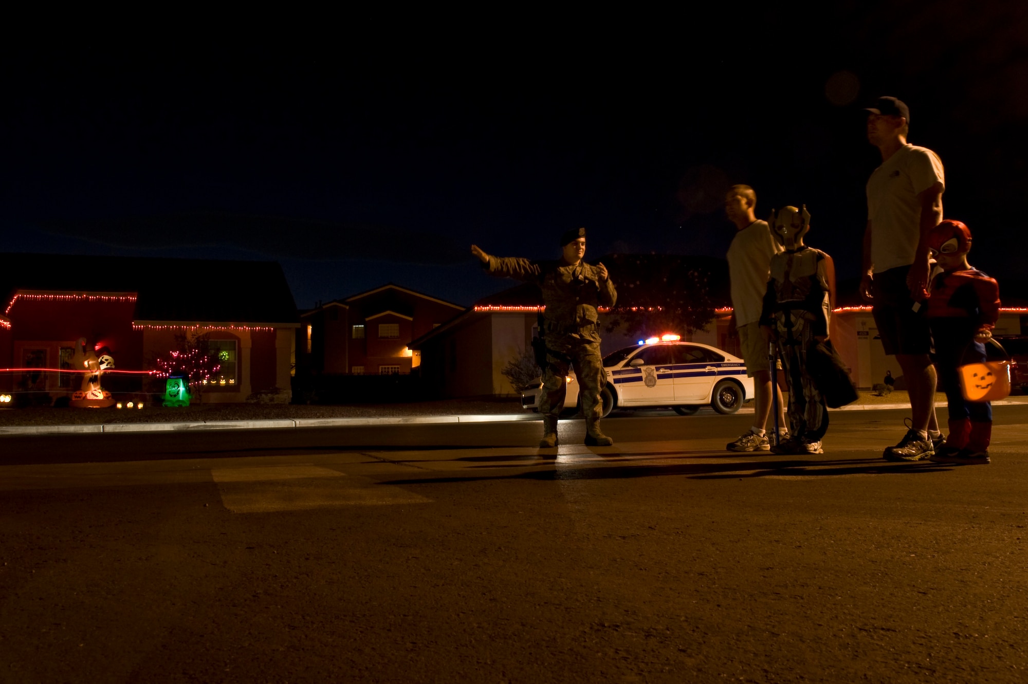 U.S. Air Force Staff Sgt. William O' Brien, 99th Security Forces Squadron, directs traffic at a crosswalk for families trick or treating in base housing, at Nellis Air Force Base, Nev. The 99th SFS participates in Pumpkin Patrol, in which SFS Airmen patrol Nellis base housing to ensure families stay safe.  (U.S. Air Force photo by Senior Airman Daniel Hughes)