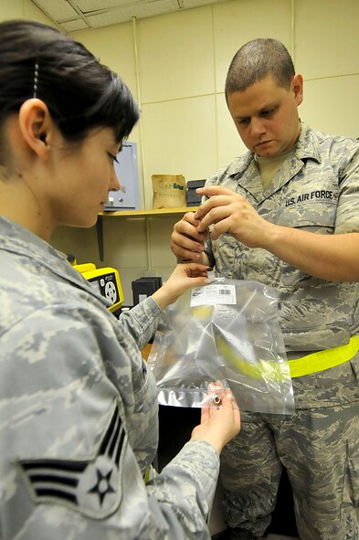 U.S. Air Force Senior Airmen Jovanna Flor, 18th Aerospace Medicine Squadron bioenvironmental engineering technician, holds the tedlar bag as U.S. Air Force Staff Sgt. Brandon Kama'i, 18th Aerospace Medicine Squadron bioenvironmental engineering technician, injects it with methanol during the third day of a Pacific Air Forces readiness inspection on Kadena Air Base, Japan, Oct. 24, 2012. The tedlar bag will be connected to purge the hapsite allowing for a clear reading without the risk of a false reading from previous tests. These Airmen keep their equipment ready at all times in case they are called to respond to a scenario. (U.S. Air Force photo/Staff Sgt. Darnell T. Cannady)