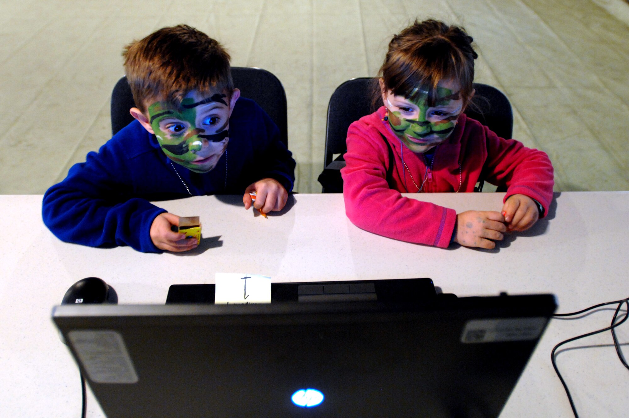 Keiyan Moreno, 6, and Leah Moreno, 5, communicate with their parents from inside the Skype tent set up at a Grand Forks Air Force Base, N.D., hangar bay for the Family Deployment Line Oct. 20, 2012. Nearly 250 family members got a glimpse of life as a deployed Airman through the event, sponsored by the Airman & Family Services Flight. The purpose of the event was to give families the opportunity to show children ages 3-16 a firsthand look at what Airmen experience when preparing for a deployment. (U.S. Air Force photo/Senior Airman Susan L. Davis)