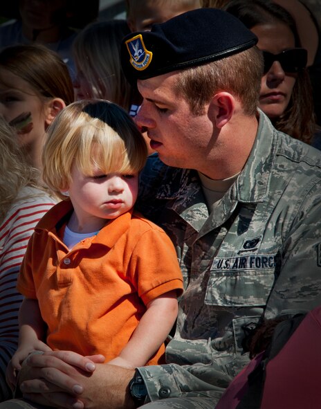 Senior Airman Jordan Hoover, 96th Test Wing Security Forces Squadron, whispers to his son McCoy before the 96th Ground Combat Training Squadron’s demonstration during Operation Hero at Eglin Air Force Base, Fla., Oct. 20. The event, sponsored by the 96th Test Wing Airman and Family Readiness Center, teaches children the experiences their military family members go through during predeployment and while out in the field. (U.S. Air Force photo/Randy Gon)