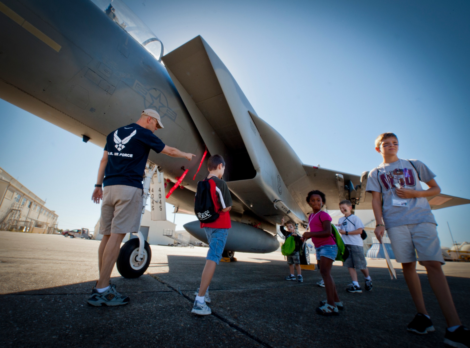 A parent and group of children find shade under an F-15 Eagle during Operation Hero at Eglin Air Force Base, Fla., Oct. 20. More than 250 children registered for the event, sponsored by the 96th Test Wing Airman and Family Readiness Center.  Operation Hero teaches children the experiences their military family members go through during predeployment and while out in the field. (U.S. Air Force photo/Randy Gon)