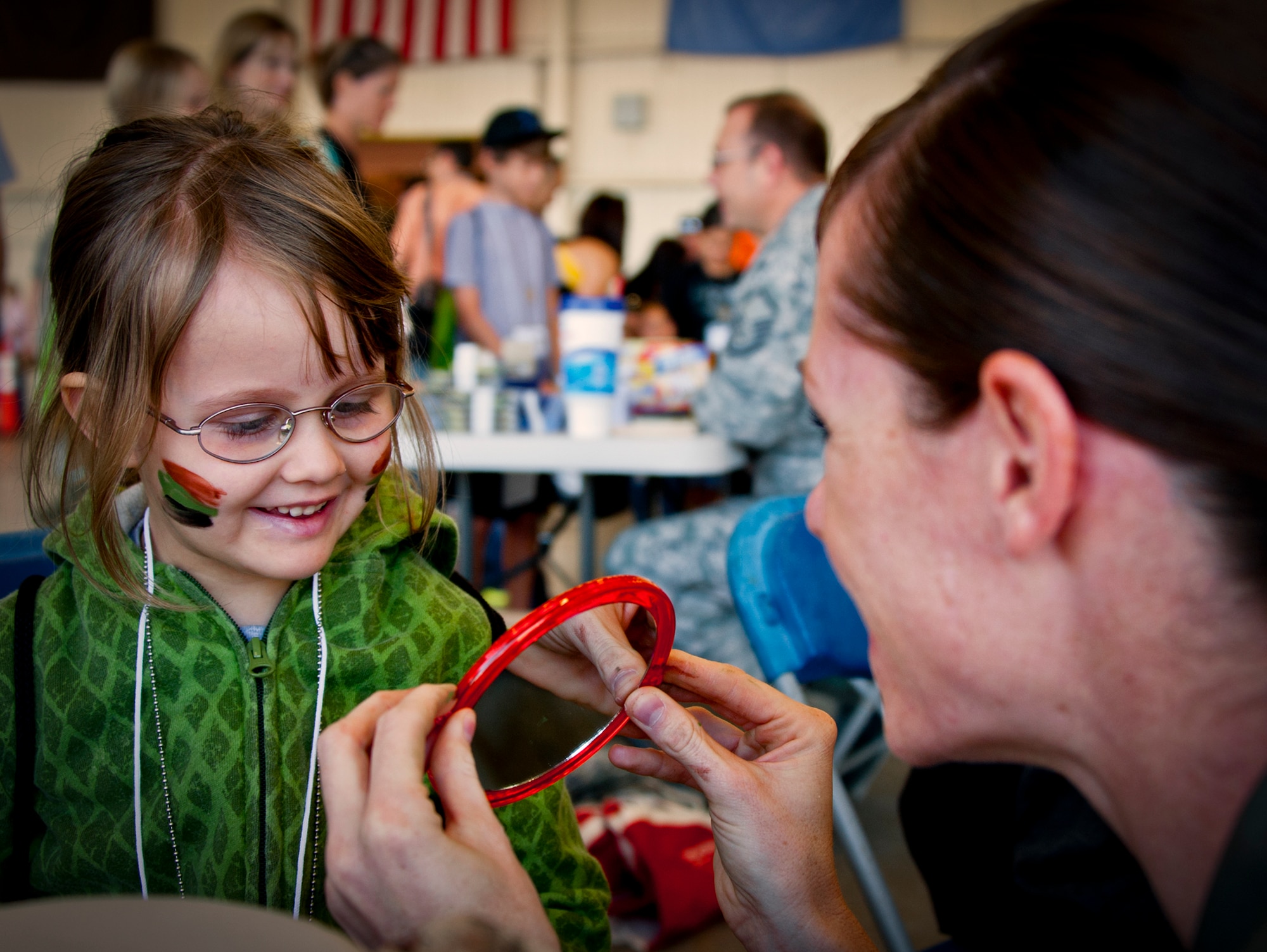 Capt. Kathy Konops, 9th Special Operations Squadron, reveals to Violet Bellino her camouflage face paint, during Operation Hero at Eglin Air Force Base, Fla., Oct. 20. Violet’s father, Sgt. Michael Bellino, is with the Marine Fighter Attack Squadron 501. The event, sponsored by the 96th Test Wing Airman and Family Readiness Center, teaches children the experiences their military family members go through during predeployment and while out in the field. (U.S. Air Force photo/Randy Gon)