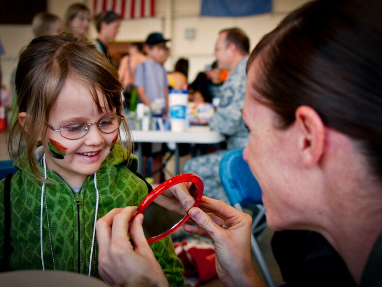 Capt. Kathy Konops, 9th Special Operations Squadron, reveals to Violet Bellino her camouflage face paint, during Operation Hero at Eglin Air Force Base, Fla., Oct. 20. Violet’s father, Sgt. Michael Bellino, is with the Marine Fighter Attack Squadron 501. The event, sponsored by the 96th Test Wing Airman and Family Readiness Center, teaches children the experiences their military family members go through during predeployment and while out in the field. (U.S. Air Force photo/Randy Gon)