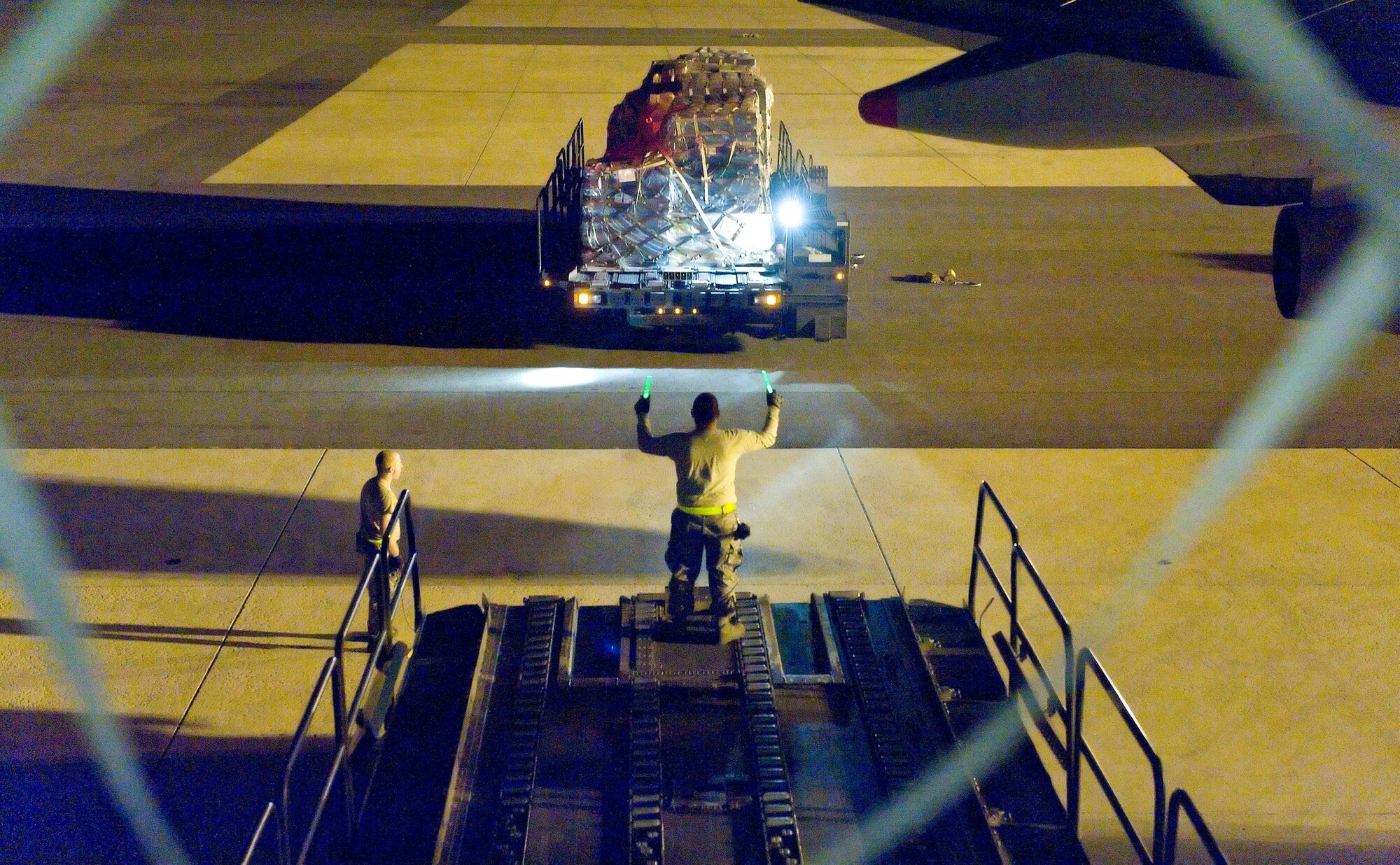 Staff Sgt. Julio Lopez, a ramp operations supervisor with the 436th Aerial Port Squadron, marshals in a k-loader Oct. 21, 2012, at Dover Air Force Base, Del. Lopez and other aerial porters load and unload cargo on civilian and military aircraft at all hours of the night. (U.S. Air Force photo by Roland Balik)