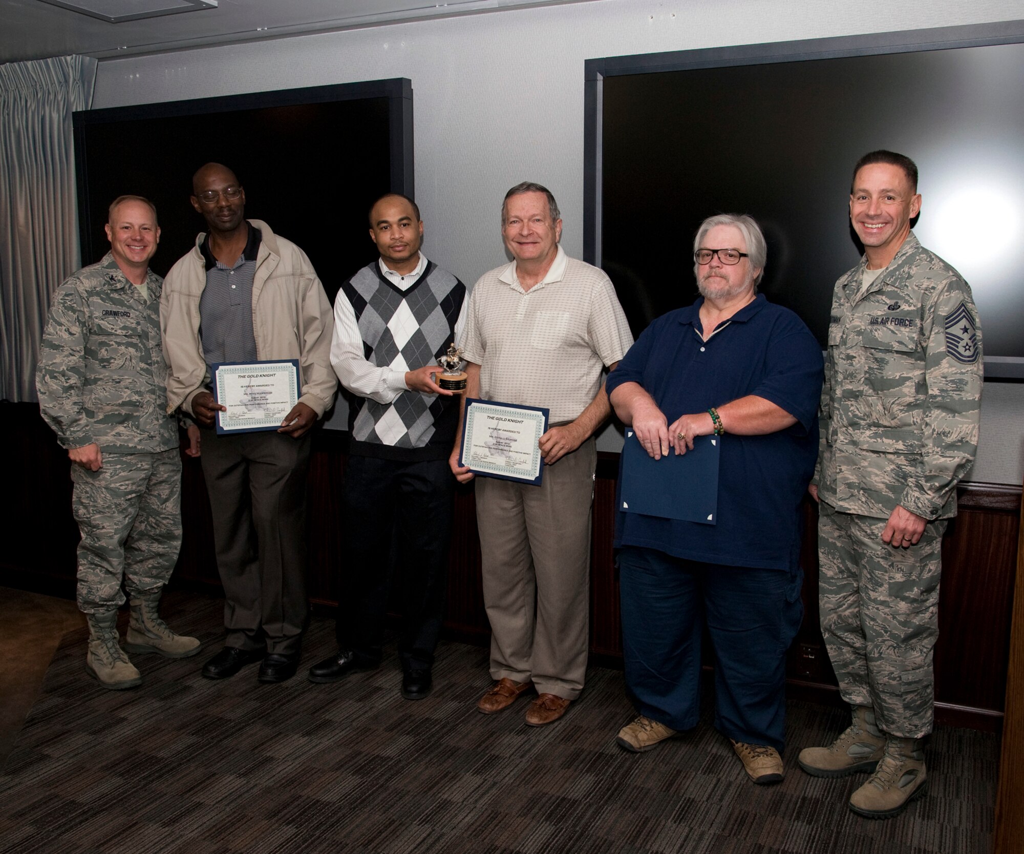 PETERSON AIR FORCE BASE, Colo. -- Col. Chris Crawford (left) 21st Space Wing commander, and Chief Master Sgt. Richard Redman (right), 21st SW command chief, present the Gold Knight award to members of the 21st Communication Squadron Command Cyber Readiness Inspection preparation team. Team members readied the wing for the inspection by eliminating thousands of vulnerabilities and assuring the connectivity for more than 1,500 users. The wing received an outstanding grade for NIPRNet and an excellent grade for SIPRNet, exceeding the Air Force average. (U.S. Air Force photo/Craig Denton)