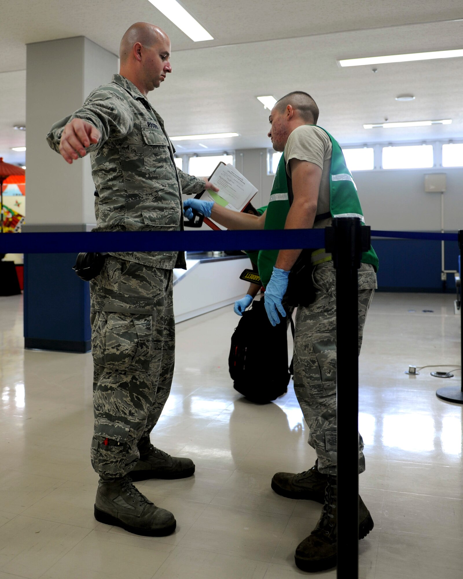 U.S. Air Force Airman 1st Class Joshua Rogers, 18th Component Maintenance Squadron egress systems apprentice, gets searched by Airman 1st Class Bryan Rezzorico, 18th Logistics Readiness Squadron vehicle maintenance, at a security checkpoint for a deployment processing line during a Pacific Air Forces readiness inspection on Kadena Air Base, Japan, Oct. 23, 2012. Rezzorico and other Airmen were augmented to fill a security role at the passenger terminal during the inspection. (U.S. Air Force photo/Airman 1st Class Hailey R. Davis)   