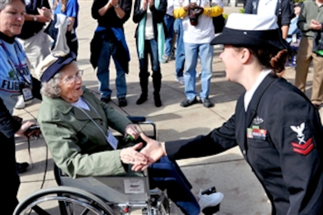 Navy Yeoman 2nd Class Erika Cash shakes hands with a World War II veteran as she enters the World War II Memorial during the Joint Services Make a Difference Day in Washington, D.C., Oct. 20, 2012. Approximately 525 veterans participated in the Honor Flight Network program, which transports America's veterans to Washington, D.C., to visit those memorials dedicated to honor their service and sacrifices. Cash is assigned to Military Sealift Command.