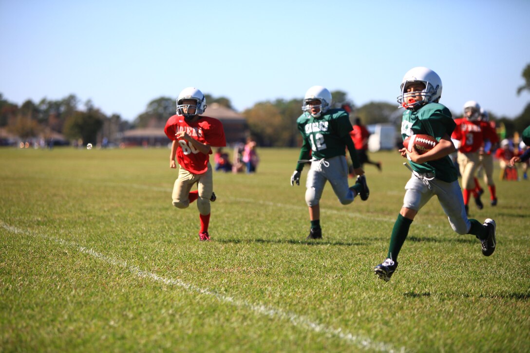 A member of the Eagles, a youth football team aboard Camp Lejeune, N.C., drives towards the end zone Oct. 20, 2012. Gunnery Sgt. Jesus M. Melendrez, the operations chief for Combat Logistics Regiment 25, 2nd Marine Logistics Group, coached the Eagles to victory in the game as part of his daily routine of volunteering with young athletes on base. 
