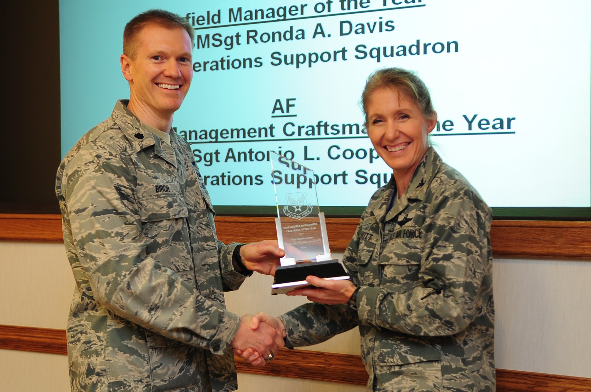 U.S. Air Force Lt. Col. Paul Birch, 4th Operations Support Squadron commander, accepts an award from Col. Jeannie Leavitt, 4th Fighter Wing commander, during a meeting on Seymour Johnson Air Force Base, N.C., Oct. 16, 2012. Birch accepted the 2011 Air Force Airfield Management Craftsman of the Year award on behalf of Master Sgt. Antonio Cooper, 4th OSS airfield management craftsman. (U.S. Air Force photo/Airman 1st Class Aubrey White/Released)