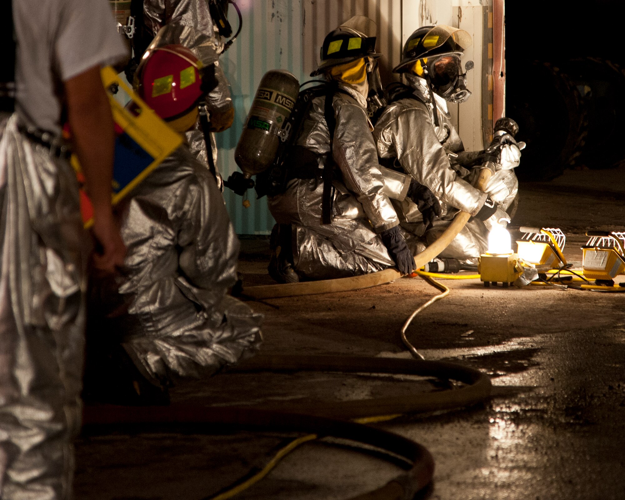 ALTUS AIR FORCE BASE, Okla. -- Firefighters from the 97th Civil Engineer Squadron fire department prepare a fire hose while responding to a fire at a vacant building on base Oct. 24, 2012. The building was unoccupied and was in the process of being demolished. The cause of the fire is unknown at this time. (U.S. Air Force photo by Senior Airman Kenneth W. Norman / Released)