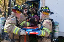 HANSCOM AIR FORCE BASE, Mass. - Hanscom firefighters (left to right) Michael Sullivan, Keith Williams, Casey Videtto and Kevin Tanguay “rescue” Staff Sgt. April Castro, Chapel Operations NCO in charge, from a simulated overturned vehicle Oct. 17. The rescue was one of three base readiness exercise scenarios conducted as part of the three-day event. (U.S. Air Force photo by Rick Berry)