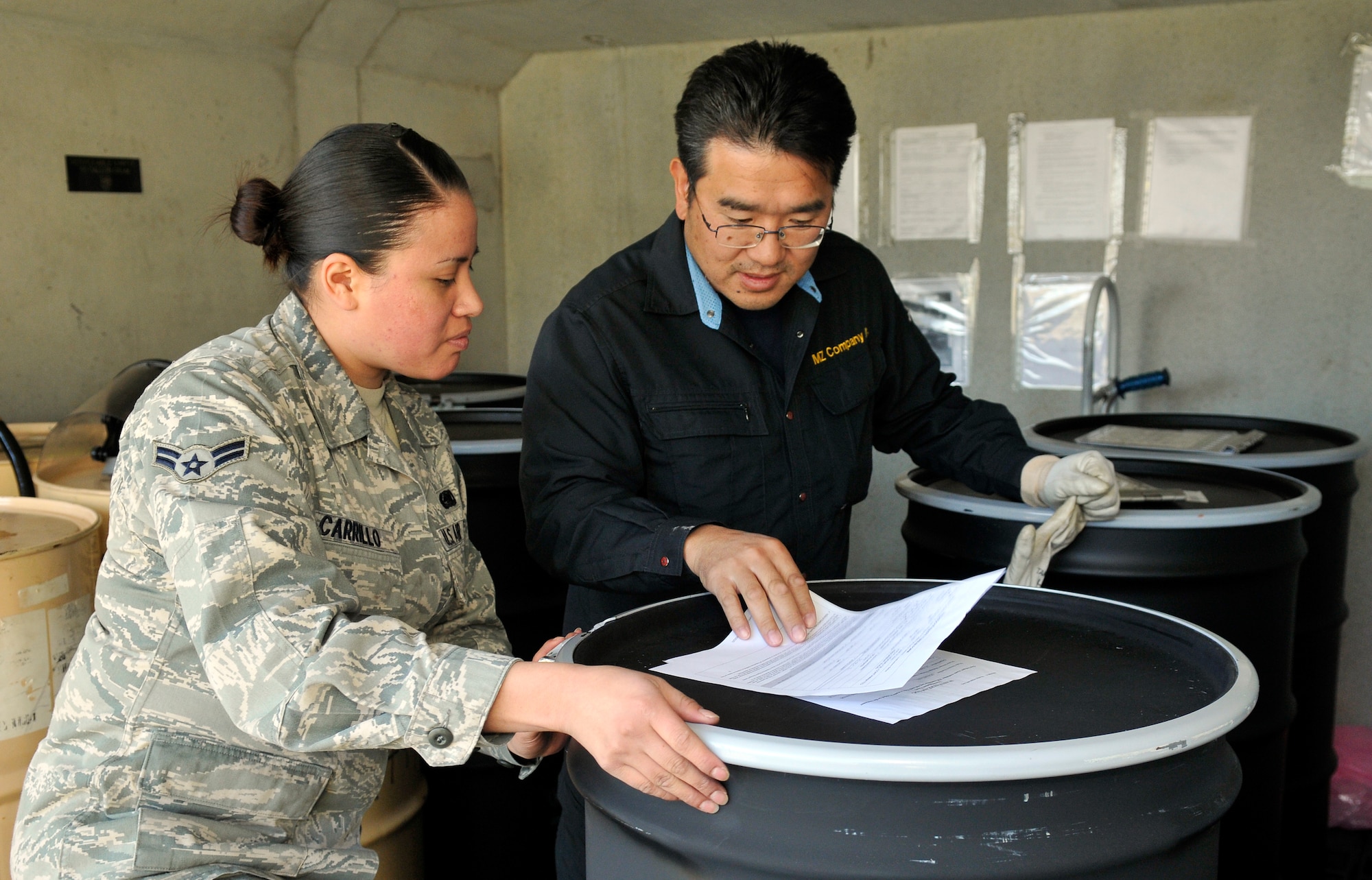 U.S. Air Force Airman 1st Class Gabrielle Carrillo, 13th Aircraft Maintenance Unit supply apprentice, and Koji Takayama, hazardous waste storage area site manager, check hazardous material transfer documentation for accuracy at Misawa Air Base, Japan, Oct. 24, 2012.  Each barrel of waste is individually numbered and the number can be traced back to the collection point years after being collected. (U.S. Air Force photo by Tech. Sgt. Phillip Butterfield) 

