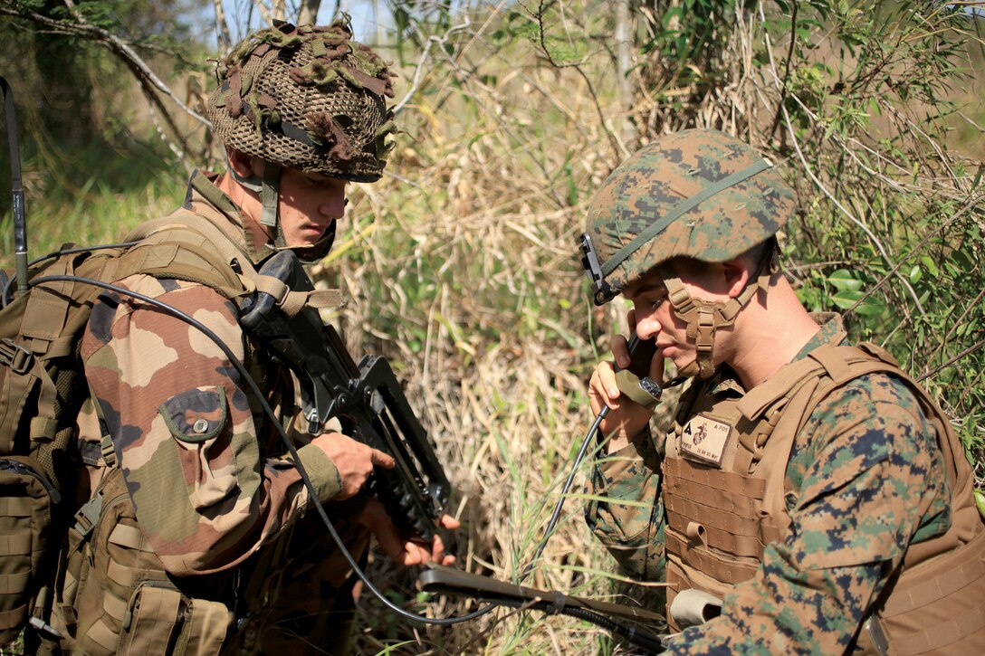 French Marine Pfc. Christopher Bazin, left and U.S. Marine Lance Cpl. David C. Poynter call in a simulated enemy improvised explosive device sighted on a patrol during Exercise Croix du Sud at Camp la Broche, New Caledonia, Oct. 13. The French and U.S. Marines were each given a bridge and area to secure as part of a multilateral, company-level attack. Poynter is a radio operator with 1st platoon, Company G, 2nd Battalion, 3rd Marine Regiment, which is currently assigned to 4th Marine Regiment, 3rd Marine Division, III Marine Expeditionary Force. Bazin is a paratrooper with 8th Marine Infantry Paratrooper Regiment, based out of Castres, France. 