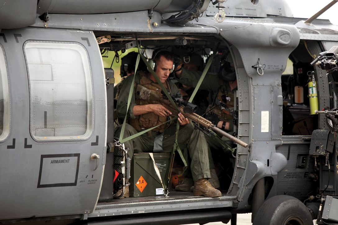 Sgt. Kyle J. Becker sets his rifle rigging system in an Air Force HH-60 Pave Hawk helicopter during aerial sniper training at Range 19 at Camp Hansen Oct. 15. The purpose of the training was to ensure the Marines are able to hit their targets from a helicopter while providing security for Marines on the ground or on a ship. Becker is a reconnaissance man with 3rd Reconnaissance Bn.  