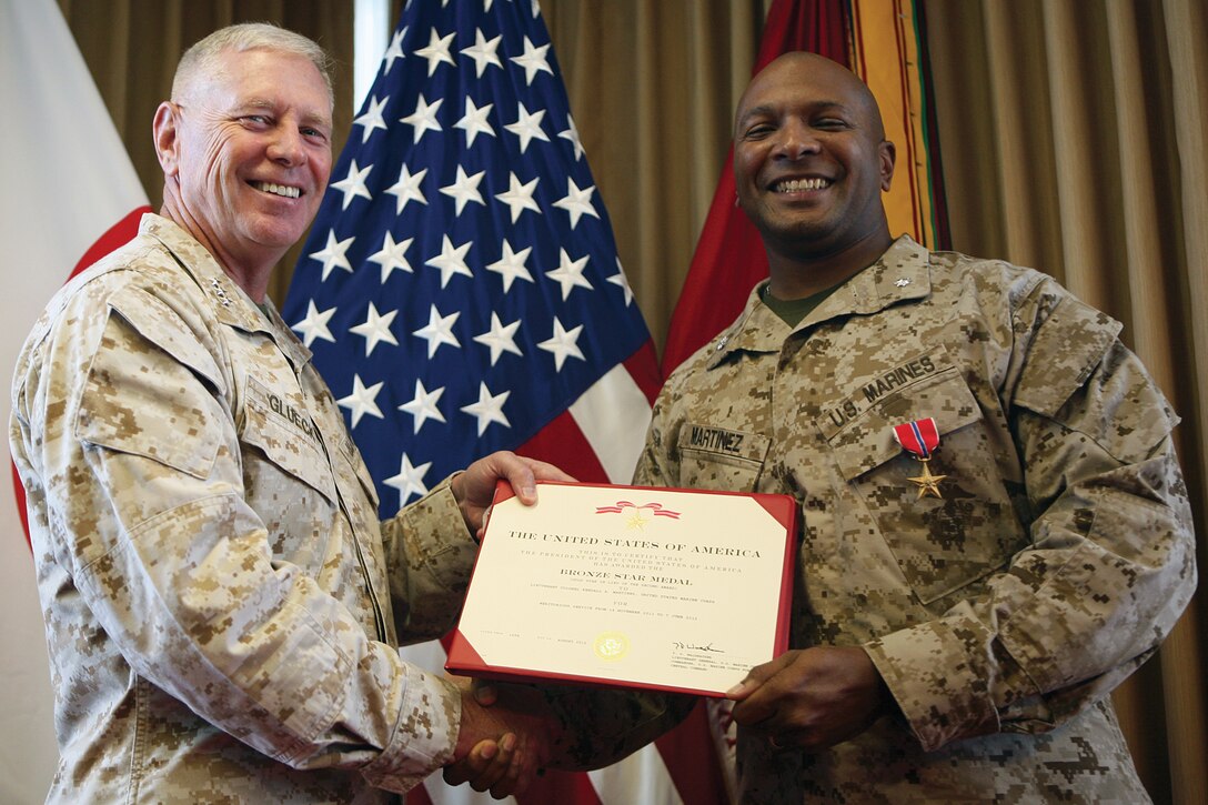 Lt. Col. Kendall A. Martinez receives a Bronze Star Medal, gold star in lieu of second award, from Lt. Gen. Kenneth J. Glueck Jr. at the III Marine Expeditionary Force headquarters building at Camp Courtney Oct. 15. The medal was awarded to Martinez for his ability to provide critical fires planning and close-air support integration in a complex battle space during combat operations against enemy forces from Nov. 14, 2011, to June 7, 2012, during Operation Enduring Freedom while serving as the commanding officer of 5th Air Naval Gunfire Liaison Company, I MEF (Forward). Glueck is the commanding general for III MEF. 