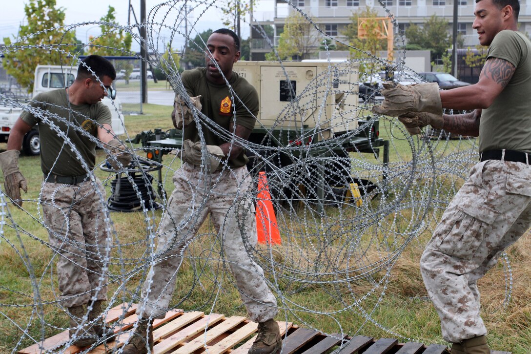 (Left to right) Lance Cpl. Gustavo Moreno, Marine Aircraft Group 12 aviation operations specialist, Sgt. Ryan Harris, MAG-12 intelligence specialist and Sgt. Cristhian Santana, MAG-12 administration specialist, set up concertina wire around the perimeter of an expeditionary command operations center aboard Marine Corps Air Station Iwakuni Oct. 17, 2012. The COC was built to ensure the Marines could deploy a system in an efficient and timely manner.