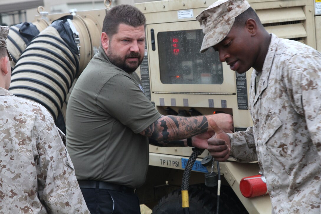 Lance Cpl. Wendell Brown, Marine Aircraft Group 12 Marine Air-Ground Task Force planner, works with Justin Grove, MAGTF communicative systems training engineer with Mystic Okinawa Command Operations Center equipment trainer, while inside the expeditionary command operations center aboard Marine Corps Air Station Iwakuni Oct. 17, 2012.