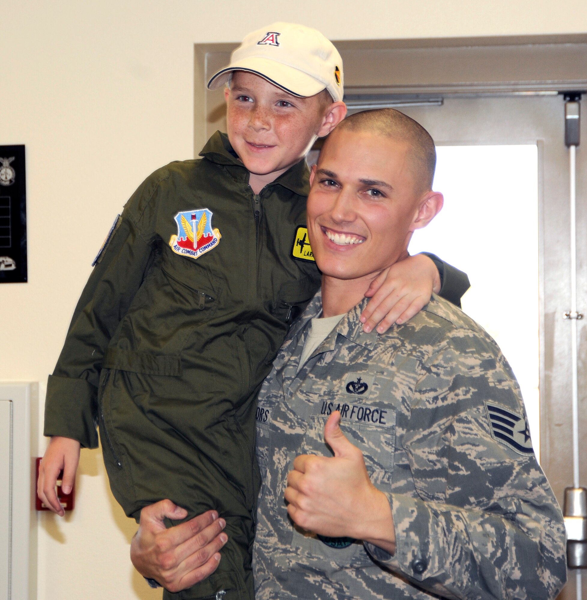 U.S. Air Force Staff Sgt. Cole Connors, 355th Civil Engineer Squadron firefighter, and Larry Ronstadt pose for a photograph after Larry's tour of the base Fire Department during the Pilot for a Day event at Davis-Monthan Air Force Base, Ariz., Oct 25, 2012.  During their visit, Larry, his father, Jeff, and grandfather, Jim, were able to tour the 357th Fighter Squadron and base Fire Department, visit an A-10 Thunderbolt and HH-60 Pavehawk static, and fly an A-10 simulator. (U.S. Air Force photo by 1LT Susan Harrington/released)