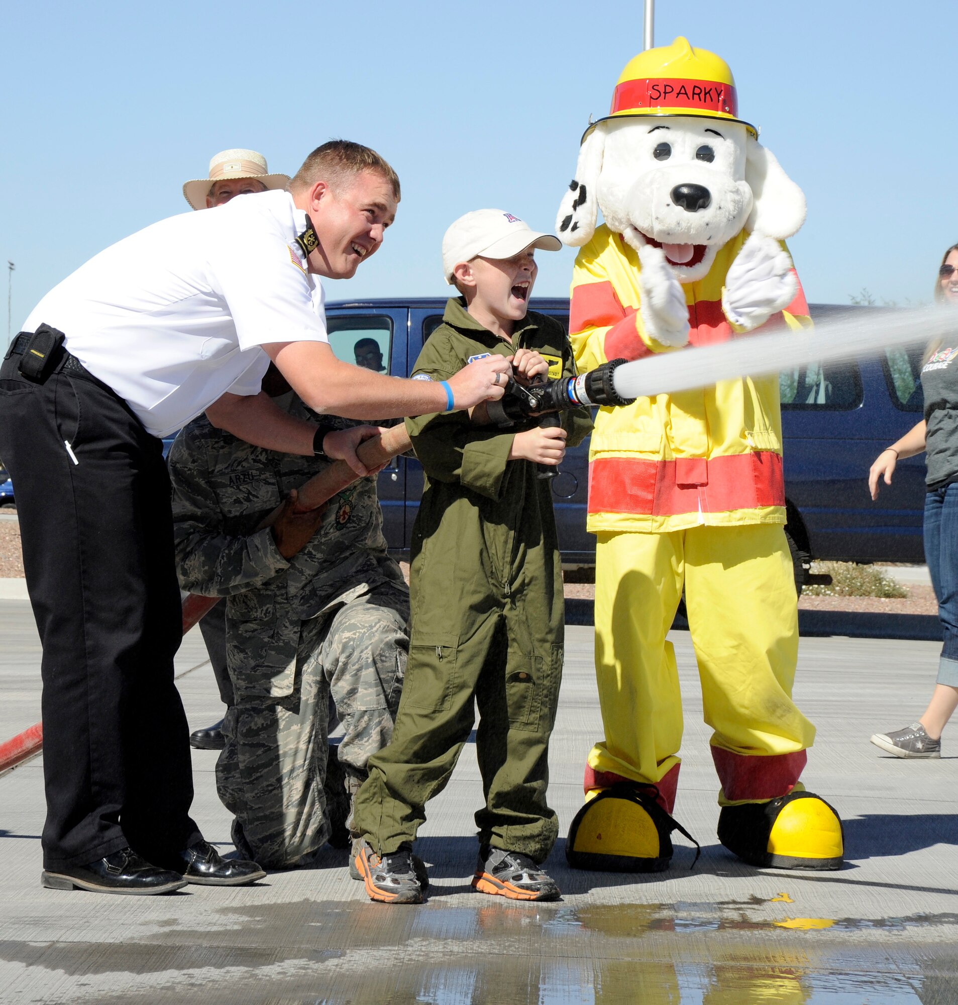 Firefighters from the Davis-Monthan Air Force Base Fire Department assist Larry Ronstadt in spraying a target with the fire hose during the Pilot for a Day event on Oct 25, 2012.  Eight-year-old Larry is the son of Jeff and Tiana Ronstadt, and was diagnosed with acute lymphoblastic leukemia in December 2011. (U.S. Air Force photo by 1LT Susan Harrington/released)