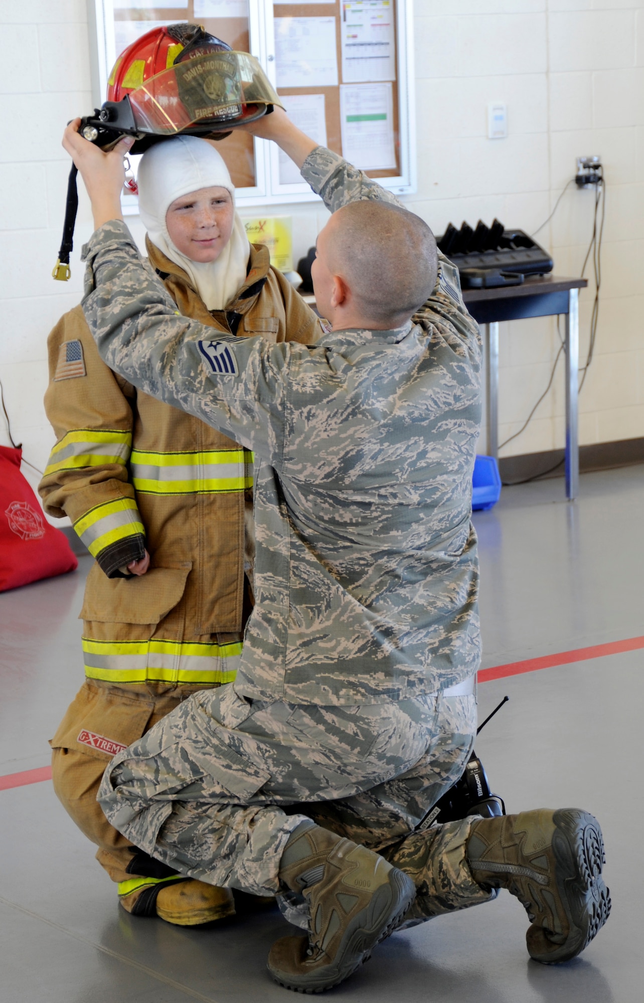 U.S Air Force Staff Sgt. Cole Connors, 355th Civil Engineer Squadron firefighter, assists Larry Ronstadt into fire-fighting personal protective equipment on Oct 25, 2012, during Larry's tour of the base Fire Department, as part of the Pilot for a Day program at Davis-Monthan Air Force Base, Ariz.  Larry was an honorary 357th Fighter Squadron pilot, where he, his father and grandfather toured the squadron, visited an A-10 static and simulator, an HH-60 static and the base Fire Department.  Sergeant Connors is a Firefighter Crew Chief with the base Fire Department. (U.S. Air Force photo by 1LT Susan Harrington/released)