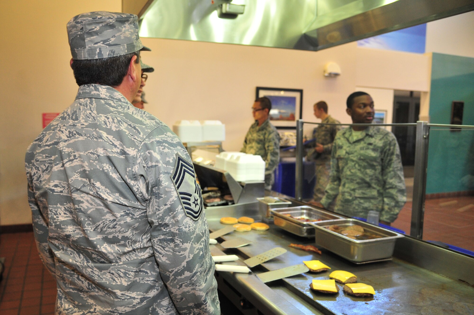 U.S. Air Force Chief Master Sgt. Edward Kirk, 27th Special Operations Logistics Readiness Squadron superintendent, works the grill in the Pecos Trail Dining Facility at Cannon Air Force Base, N.M., Oct. 26, 2012. More than a handful of chief master sergeants put on their Airman Battle Uniform hats and food-handling gloves to happily serve fellow enlisted troops and foster a more casual rapport. (U.S. Air Force photo/Airman 1st Class Alexxis Pons Abascal)  