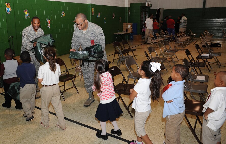Staff Sgt. Brandon Woods, left, 2nd Medical Operations Squadron Alcohol and Drug Abuse Prevention and Treatment technician, and Staff Sgt. Norris Jamison, 2 MDOS ADAPT NCO in charge, hand out U.S. Air Force tote bags to students at Bossier Elementary School, Bossier City, La., Oct. 26. Red Ribbon Week is dedicated to inform the community on the dangers of drug and alcohol abuse. Members of Team Barksdale attended the assembly to show their support for the local community. (U.S. Air Force photo/Airman 1st Class Benjamin Gonsier)(RELEASED)