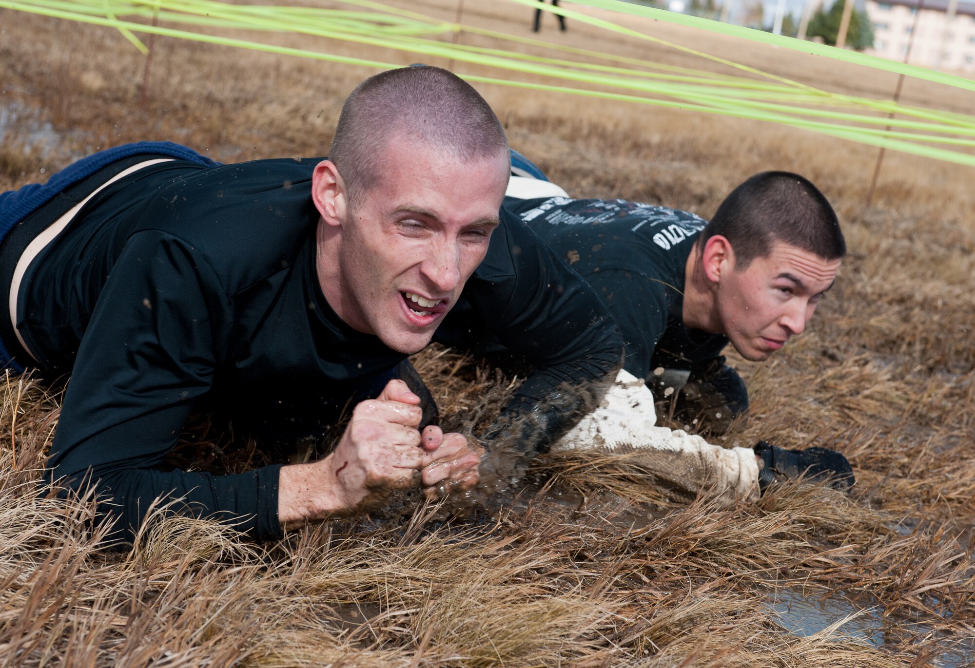 Airmen 1st Class Matthew Chroniak, 28th Maintenance Squadron nondestructive inspection technician, and Joshua Ray, 28th Civil Engineer Squadron power production specialist, low crawl through mud and water during the 2012 Mud Run at Ellsworth Air Force Base, S.D., Oct. 23, 2012. The 1.5-mile course, which included 10 different obstacles, was designed to promote National Energy Action Month, set aside each year to educate and encourage responsible domestic energy production, energy efficiency, and the development of clean energy and renewable fuels. (U.S. Air Force photo by Airman 1st Class Kate Thornton-Maurer/Released)