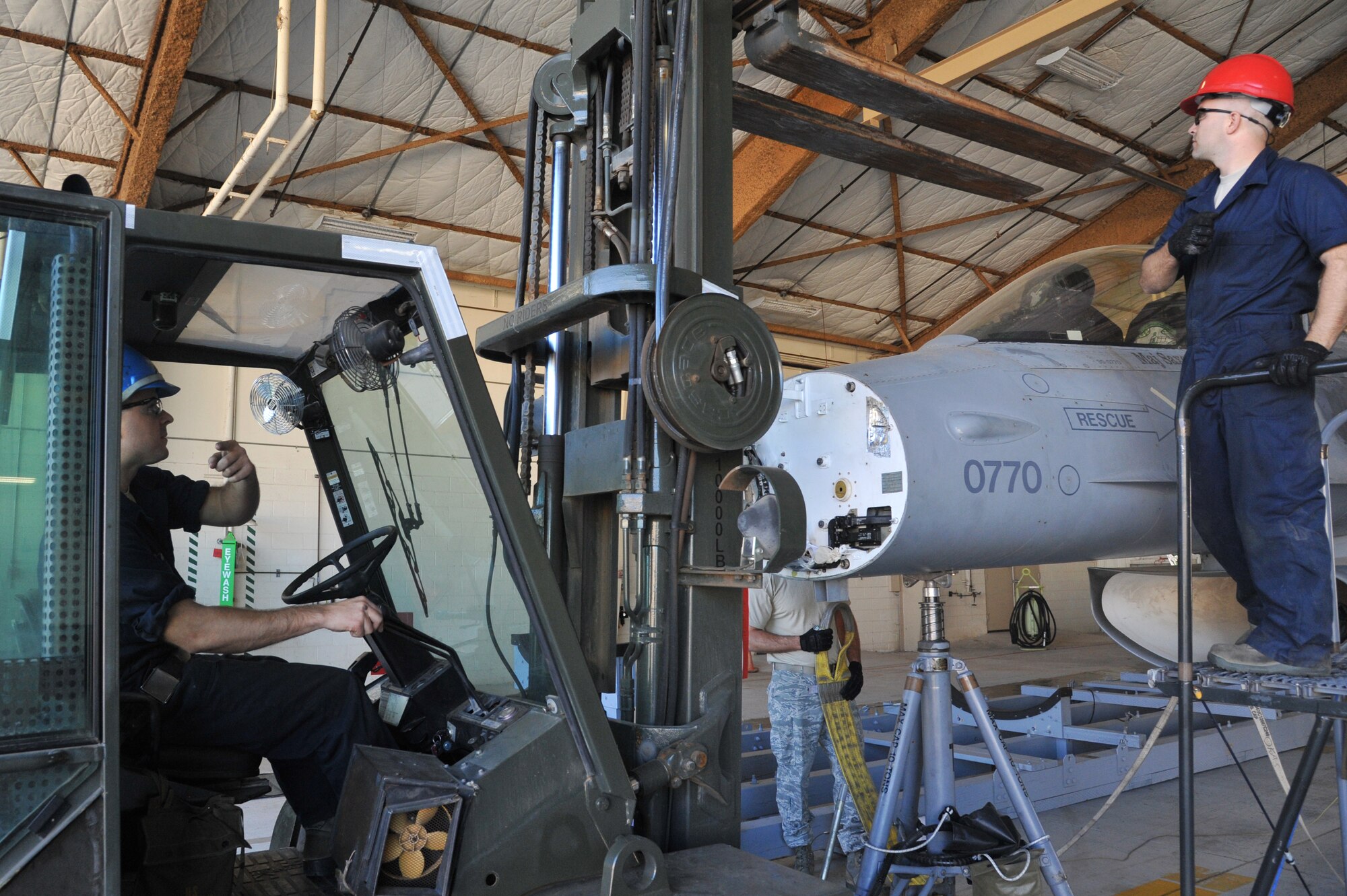 Tech. Sgt. Robert Baldwin and Staff Sgt. Jimmy Kitchens, 309th Aircraft Maintenance Group depot aircraft maintenance technicians from Hill Air Force Base, Utah, prepare to lift an F-16 Oct. 9 at Luke Air Force Base in Hangar 984. (U.S. Air Force photo by Senior Airman Sandra Welch)