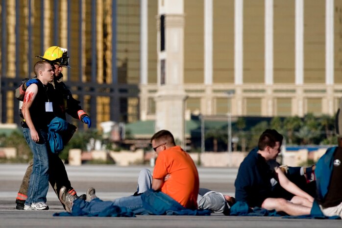 An Airman from Nellis Air Force Base walks with the assistance of a Clark County firefighter to the safety area during the 2012 Triennial Emergency Preparedness Exercise at McCarran International Airport Oct. 24, 2012, in Las Vegas, Nev. The exercise helps identify areas in which procedures should be changed or equipment added in order to enhance the emergency response capabilities. (U.S. Air Force photo by Senior Airman Daniel Hughes)