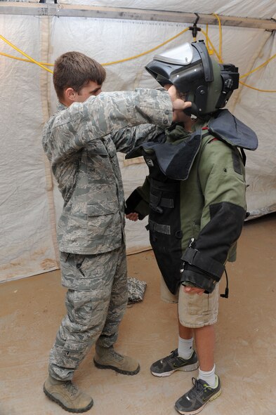 Airman 1st Class William Riddle, 56th Civil Engineer Squadron explosive ordnance disposal technician, helps Colin Cool, 13, son of Lt. Col. Bert Cool, 56th Mission Support Group deputy commander, into a bombsuit during Operation KIDS at Luke. EOD showcased their bomb suit and other tools of the trade. (U.S. Air Force photo by Airman 1st Class Devante Williams)