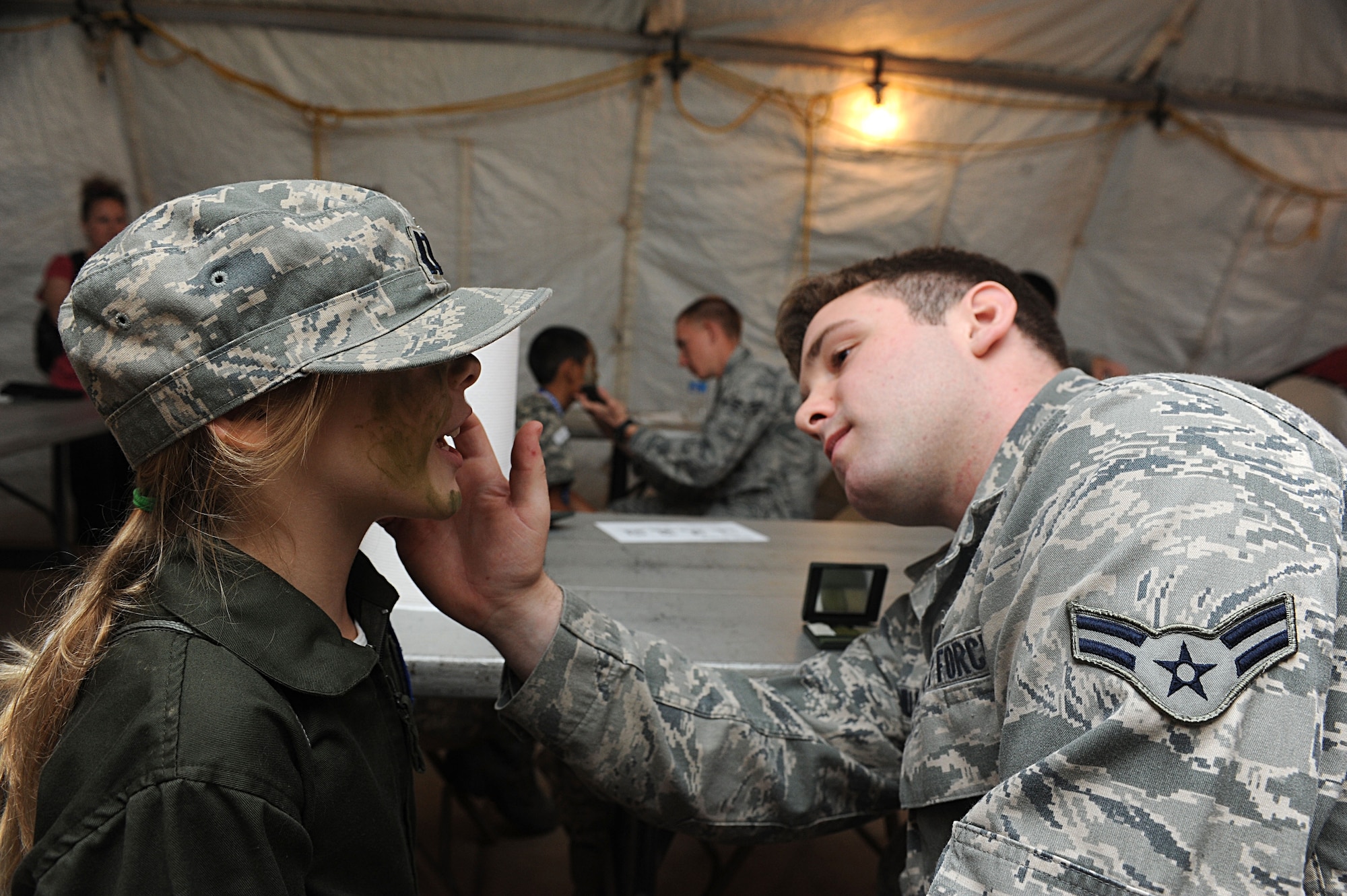 Airman 1st Class Michael Bawmiller, 56th Security Forces Squadron security patrolman, applies camo paint to the face of  Anna Jameson, 8, daughter of retired Major Stacy Jameson, during the Operation Kids event at Luke Air Force Base, Ariz. Operation Kids is designed to give children of military members a glimpse of what it is like when their parents deploy. (U.S. Air Force photo by Airman 1st Class Devante Williams)