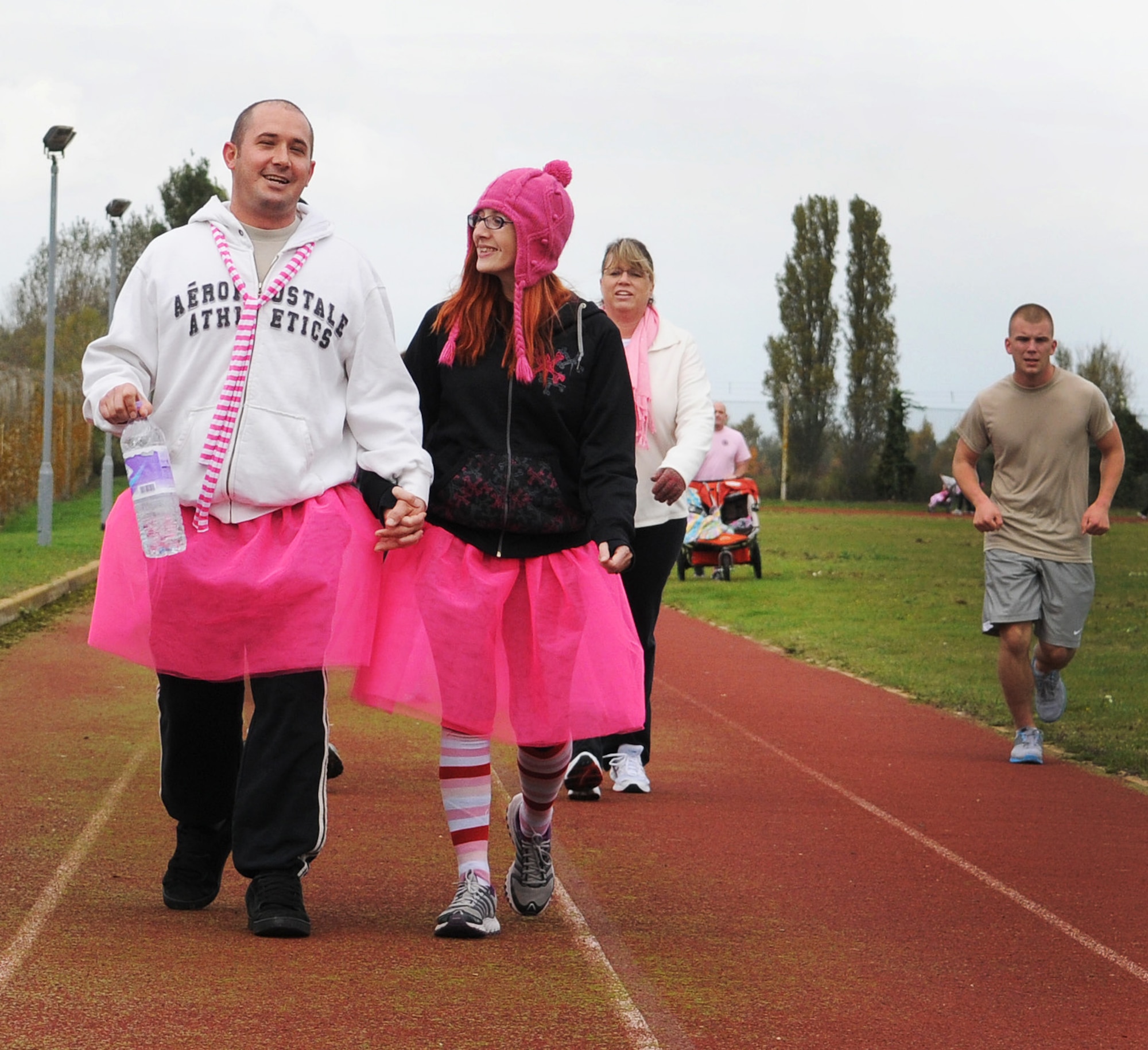 Tech. Sgt. Richard Kelly, 100th Communication Squadron cyber operations supervisor, and his wife Jessica walk the Heritage Park track in bright pink tutus during the Wear Pink Breast Cancer Awareness 5/10K Walk Oct. 26, 2012, at RAF Mildenhall, England.  Approximately 200 base members walked or ran the track in pink attire to support Breast Cancer Awareness Month. (U.S. Air Force photo by Staff Sgt. Tabitha M. Lee/Released)