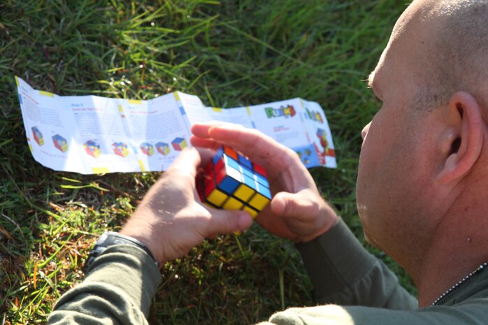 Gunnery Sgt. Michael Turner, an engineer equipment chief with 2nd Maintenance Battalion, 2nd Marine Logistics Group, tackles a Rubik’s Cube during the unit’s field meet aboard Camp Lejeune, N.C., Oct. 24, 2012. The Marines increased their heart rates through strenuous exercise before crawling to the cubes, where Turner pulled the instructions from his pocket after his first attempt to solve to puzzle failed. 