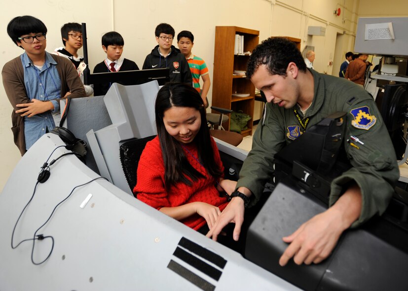 1st Lt. Josh Arnall teaches junior and high school students from eight different institutions about the F-16 Fighting Falcon flight simulators during the honorary pilot program at Kunsan Air Base, Republic of Korea, Oct. 24, 2012. The pilots use the simulators to train on anything from taking off and landing to using their weapons systems. (U.S. Air Force photo/Senior Airman Marcus Morris)