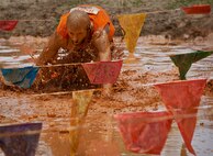 A runner scrambles through the large mudpit at the end of the Emerald Coast MudRun for Orphans May 19 in Niceville, Fla.  Active-duty and reserve service members from Duke, Hurlburt Field, Eglin and more came out to get dirty in either the morning or afternoon 5K challenges. (U.S. Air Force photo/Tech. Sgt. Samuel King Jr.)