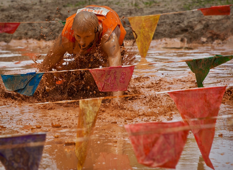 A runner scrambles through the large mudpit at the end of the Emerald Coast MudRun for Orphans May 19 in Niceville, Fla.  Active-duty and reserve service members from Duke, Hurlburt Field, Eglin and more came out to get dirty in either the morning or afternoon 5K challenges. (U.S. Air Force photo/Tech. Sgt. Samuel King Jr.)