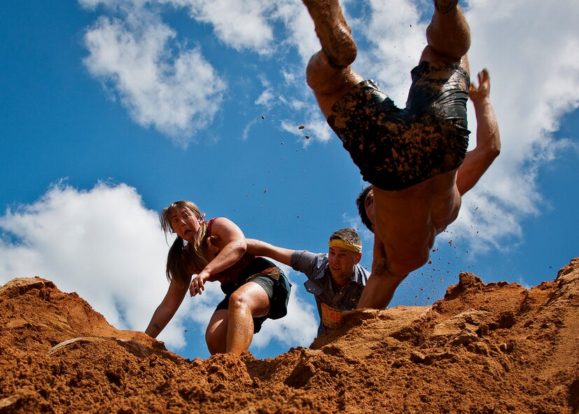 A runner reacts to her friend as he performs a flip off the top of a tall mound of dirt at the end of Emerald Coast MudRun for Orphans May 19 in Niceville, Fla.  Active-duty and reserve service members from Duke, Hurlburt Field, Eglin and more came out to get dirty in either the morning or afternoon 5K challenges. (U.S. Air Force photo/Tech. Sgt. Samuel King Jr.)