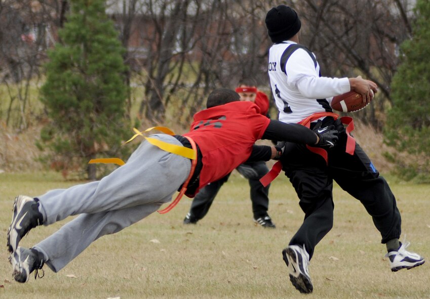 Senior Airman Christopher Horton, 319th Civil Engineering Squadron, dives to tackle Staff Sgt. Louis Cooley, 319th Security Forces Squadron, during the intramural flag football championship Oct. 27, 2012, on Grand Forks Air Force Base, N.D. The 319th SFS defeated the 319th CES by a score of 19-6. (U.S Air Force photo/Airman 1st Class Ashley Taylor)